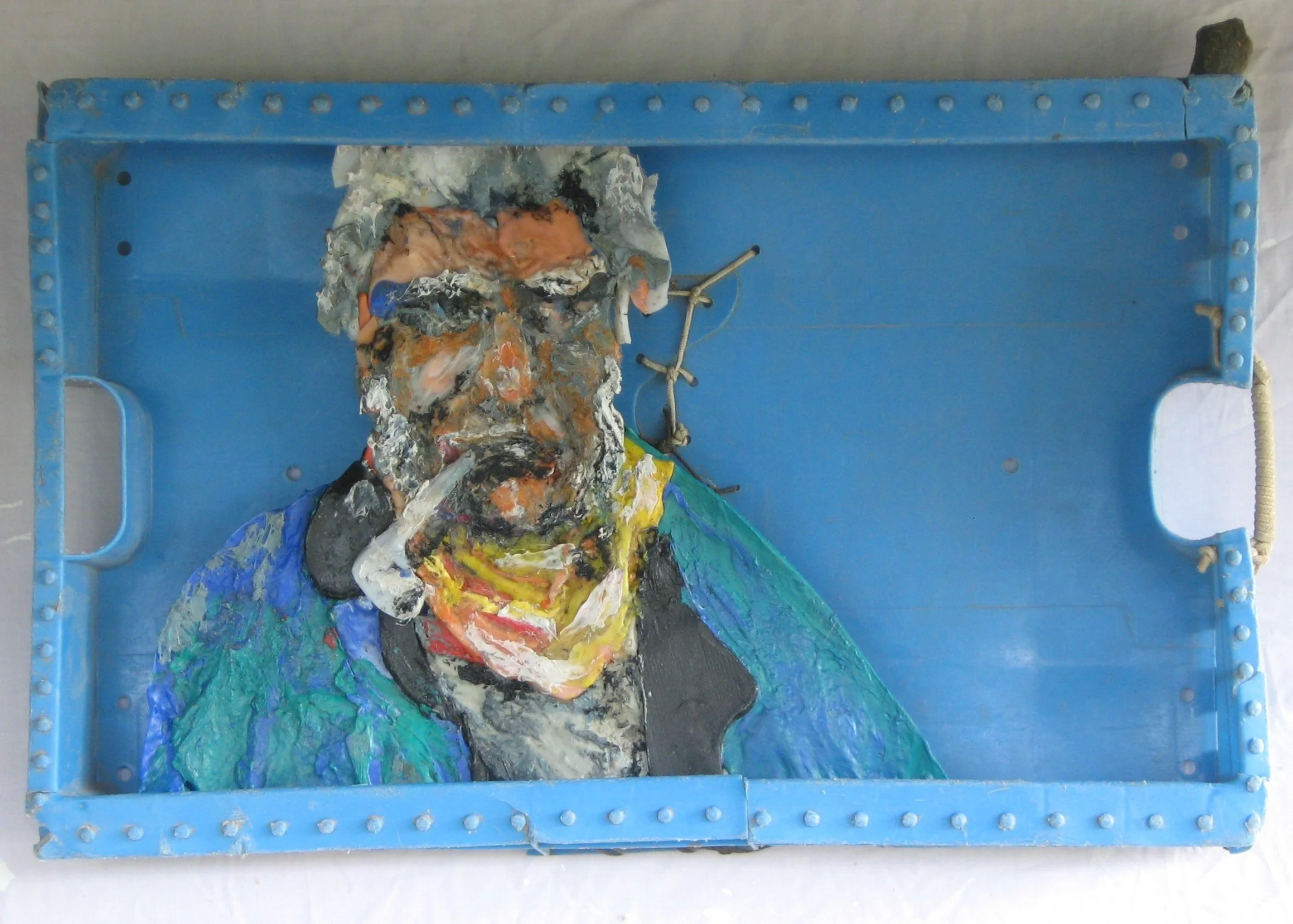 portrait of old man with his pipe made of multicoloured plastic debris melted and welded together and set in a well worn stitched together fish-boxs