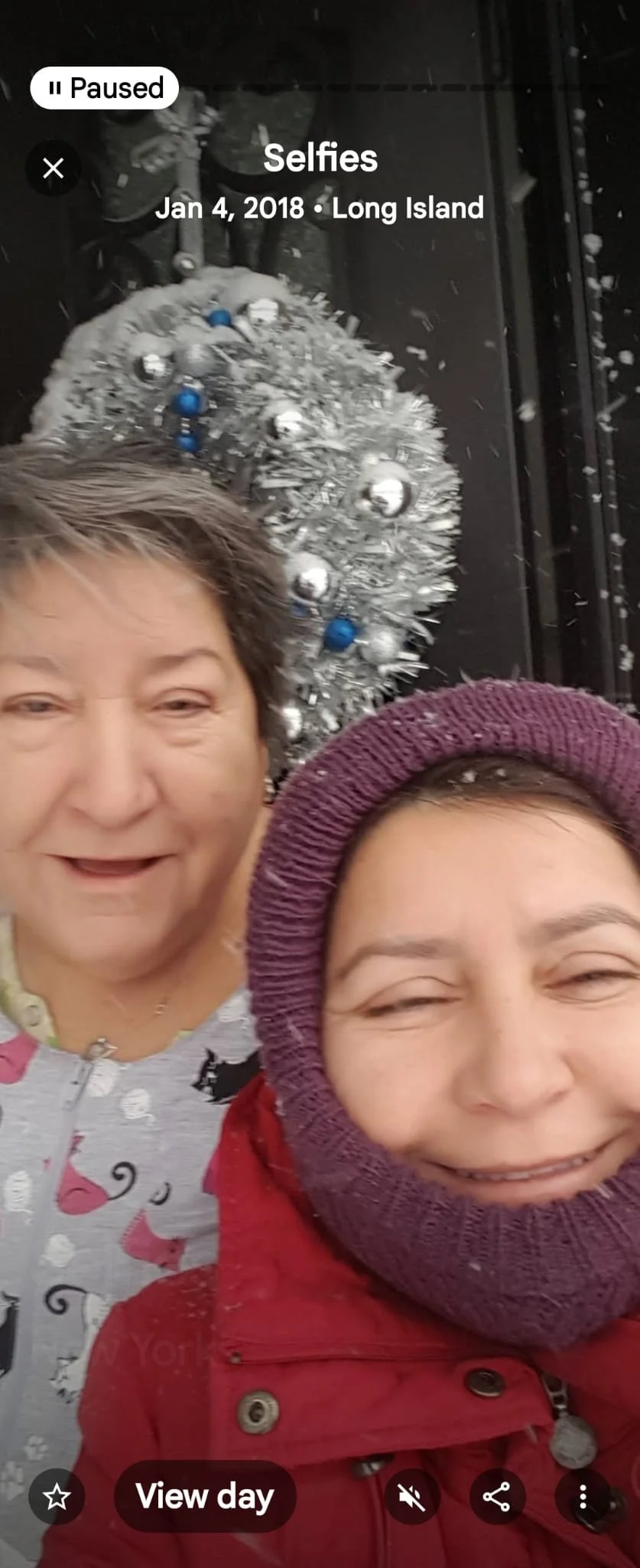 Two women in winter clothing taking a selfie in front of a decorated silver Christmas tree with blue and silver ornaments on Long Island, New York, on January 4, 2018.