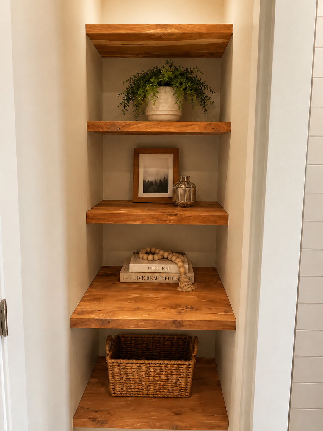 Built-in wooden shelves with decorative items including a potted plant, a framed photograph, a glass vase, and books, located in a home interior.