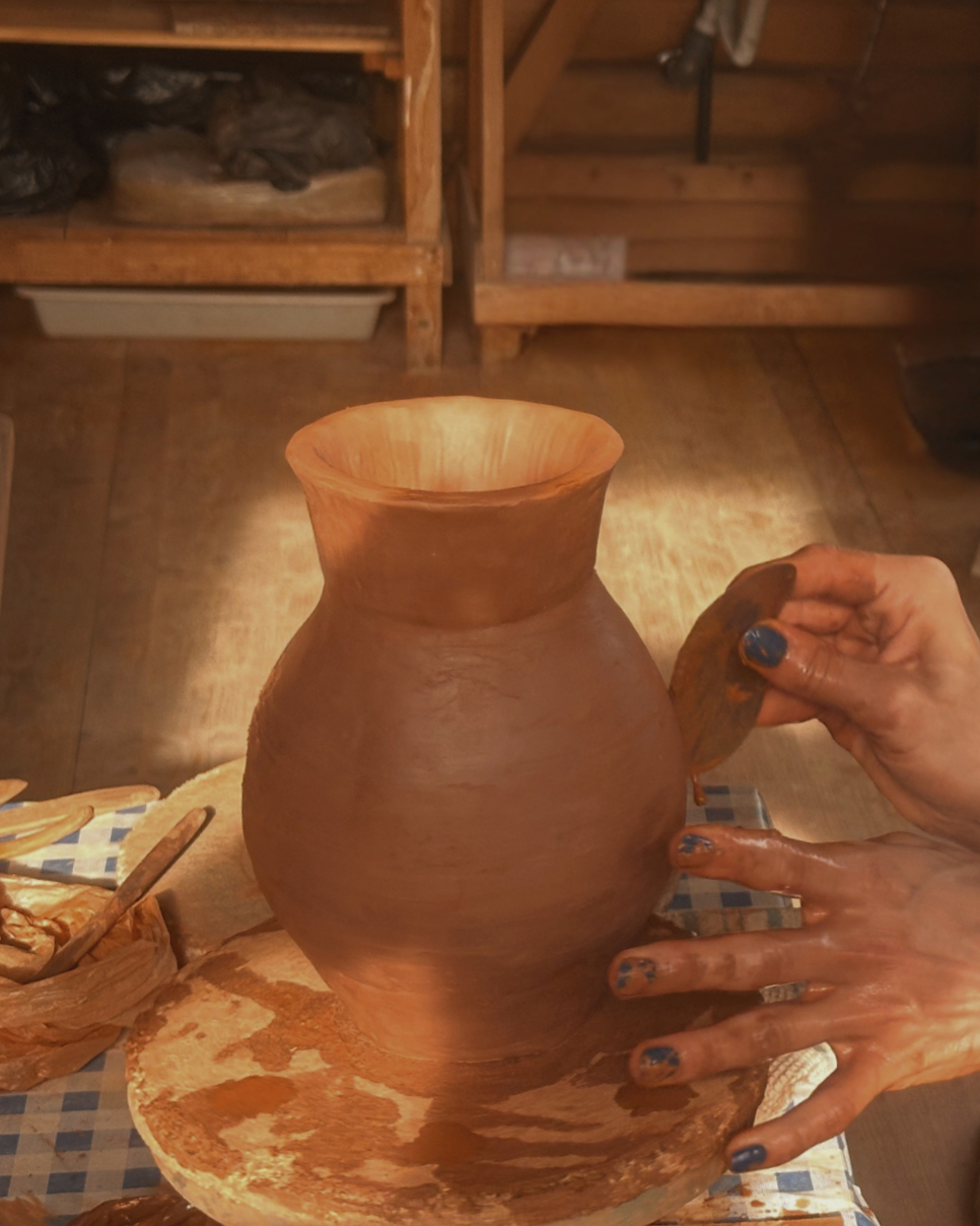 Hands shaping a terracotta vase on the pottery wheel during a ceramics retreat in Portugal