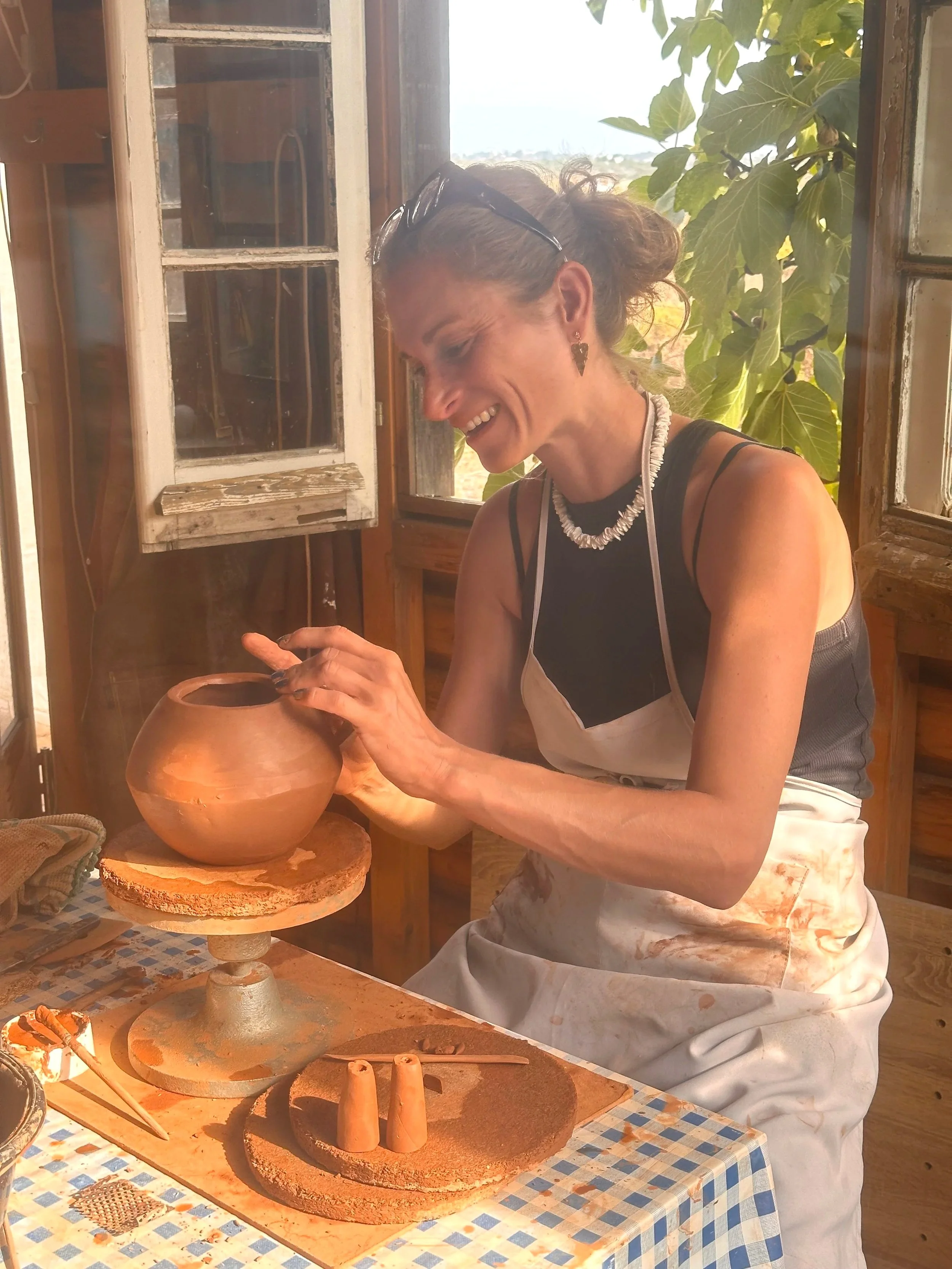 Woman throwing a pot in a rustic studio during a pottery retreat in the Algarve