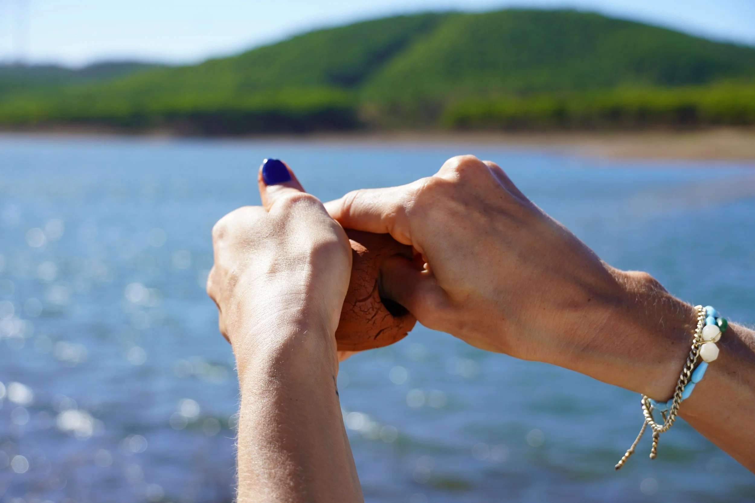 Hands shaping wet clay beside the reservoir in the western Algarve