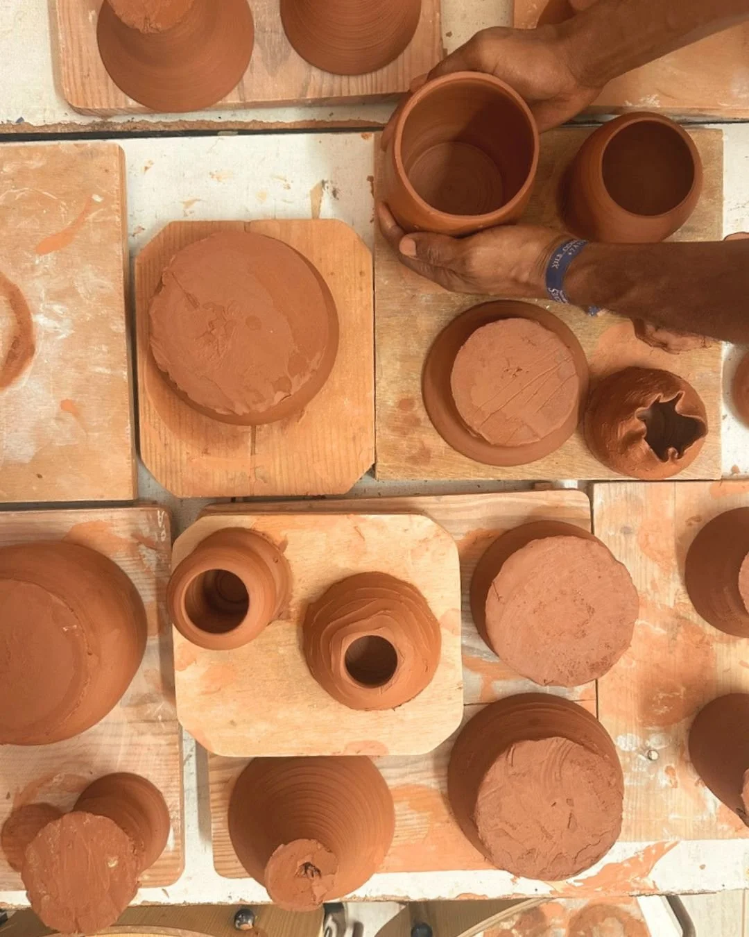 Freshly thrown terracotta pots drying on wooden boards