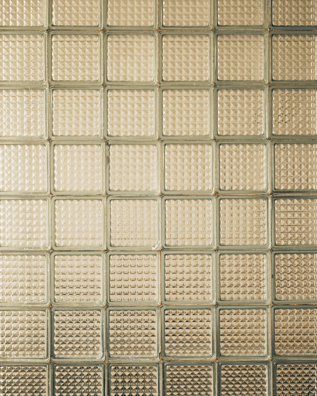 Close-up of a wall made of square glass blocks with a textured, diamond-patterned surface.