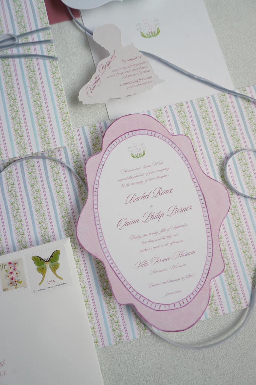 A set of wedding invitations on a patterned background, featuring a pink scalloped border and formal text, along with a small tag that says 'Kindly Reply' and a butterfly postage stamp.