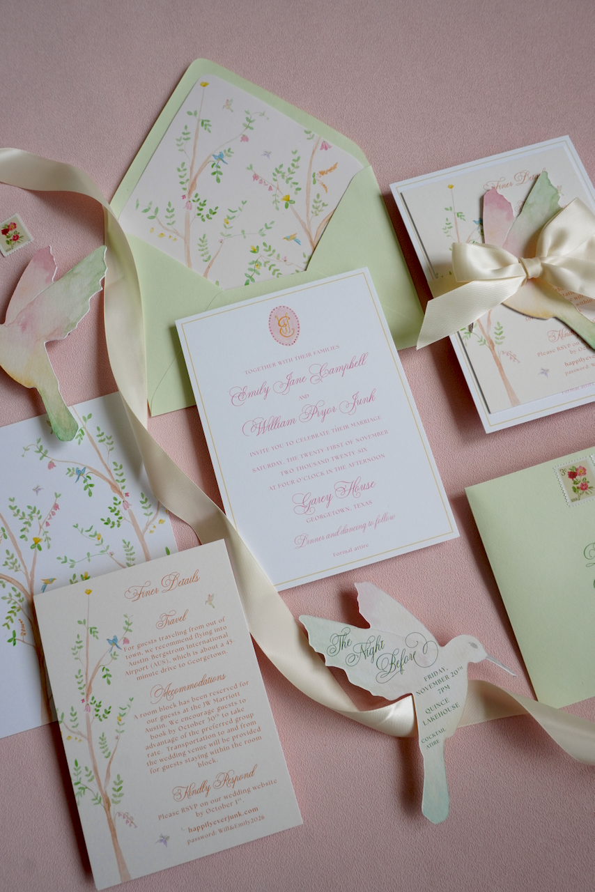Wedding invitation set with matching envelope, RSVP card, and decorative paper bird on pink background.