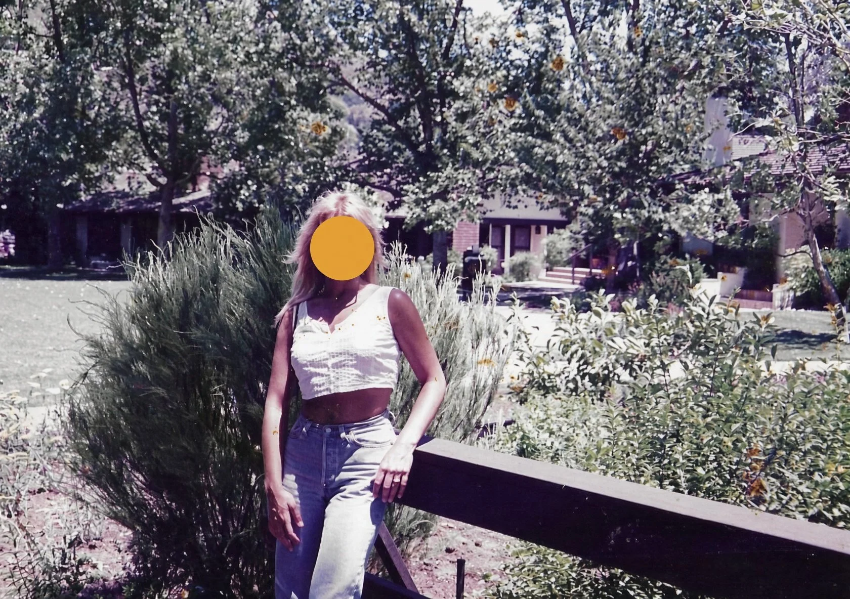 Casual outdoor portrait in a white top and jeans, face gently obscured for privacy
