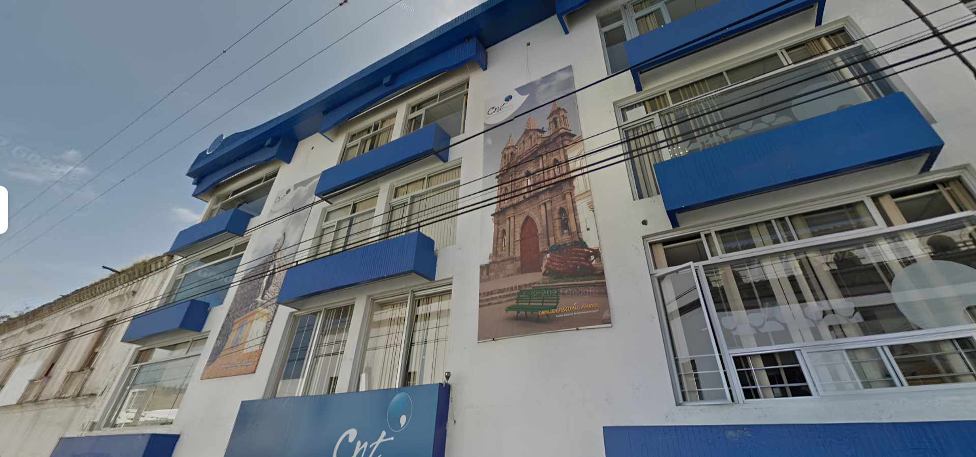 Edificio con balcones y ventanas grandes, con un cartel que muestra una iglesia histórica y la ciudad en la fachada.