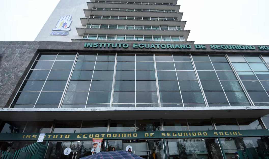 Fachada del Instituto Ecuatoriano de Seguridad Social con letras en la entrada y un edificio alto con varias plantas en el fondo