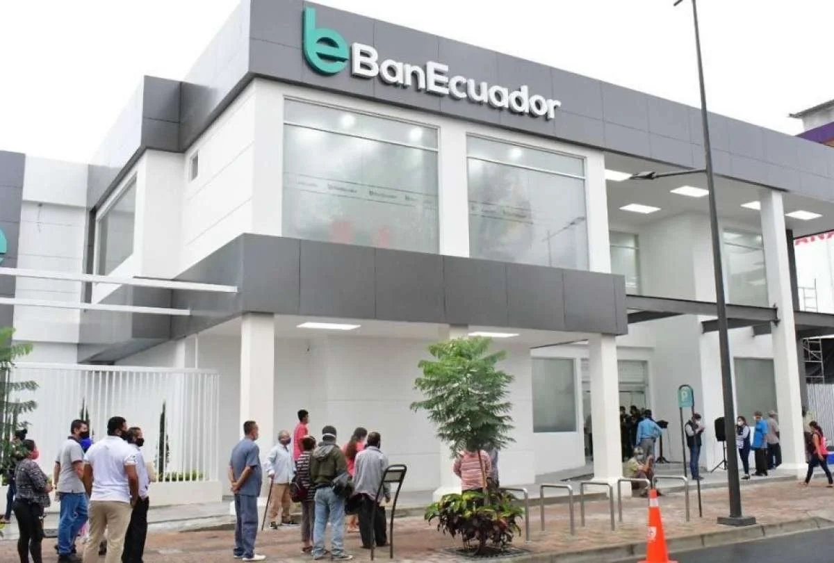 Vista del edificio del Banco de Ecuador con una fila de personas esperando en la calle.