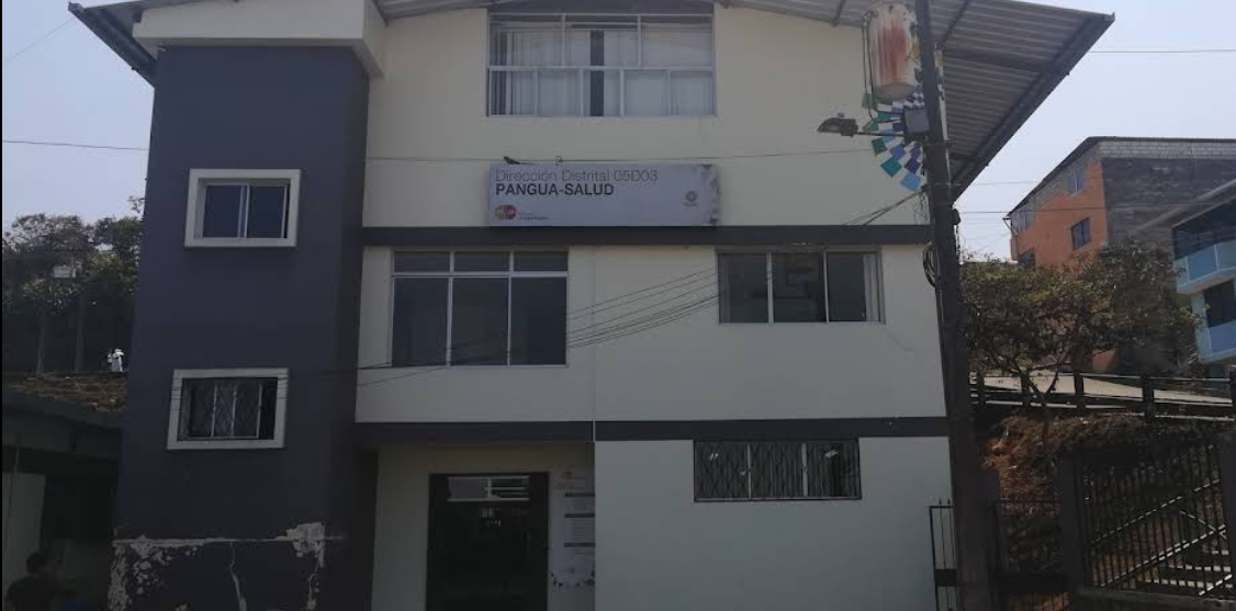 Edificio de color blanco y gris con un cartel que dice Dirección Distrital C503 PANGUA-SALUD, y tiene varias ventanas y un toldo en la parte superior.