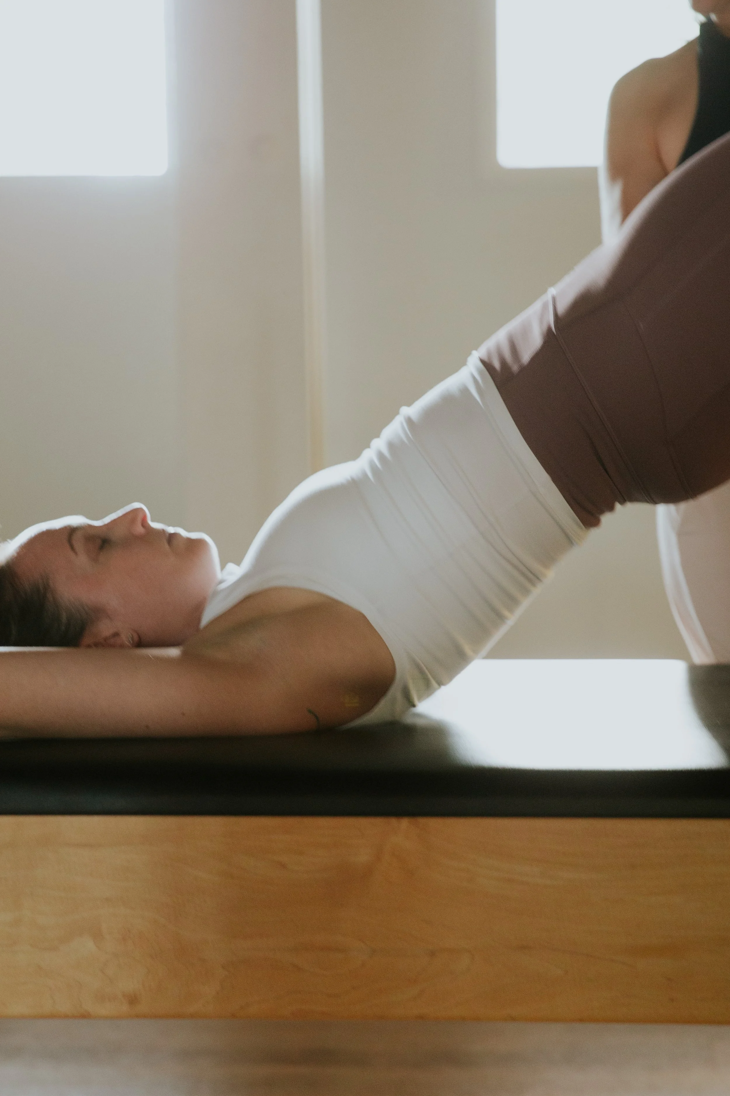 Woman lying down on a yoga mat in a peaceful indoor space, engaging in yoga or meditation exercise.