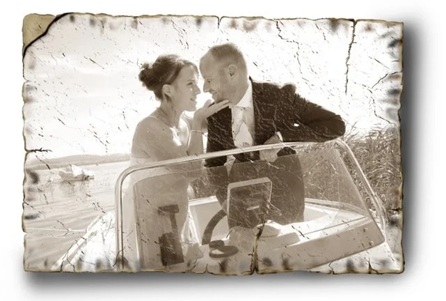 Un couple souriant dans une voiture vintage, avec un arrière-plan de mer et de ciel nuageux, photo en style ancien.