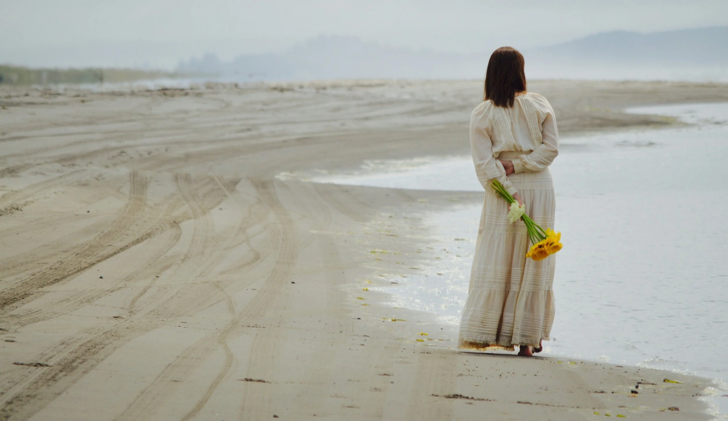 Organisatrice en robe longue avec bouquet de fleurs, organisation de mariage en Suisse Romande et France.