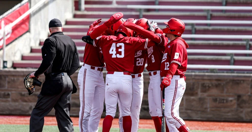 Baseball players in red uniforms celebrating on the field with an umpire nearby.