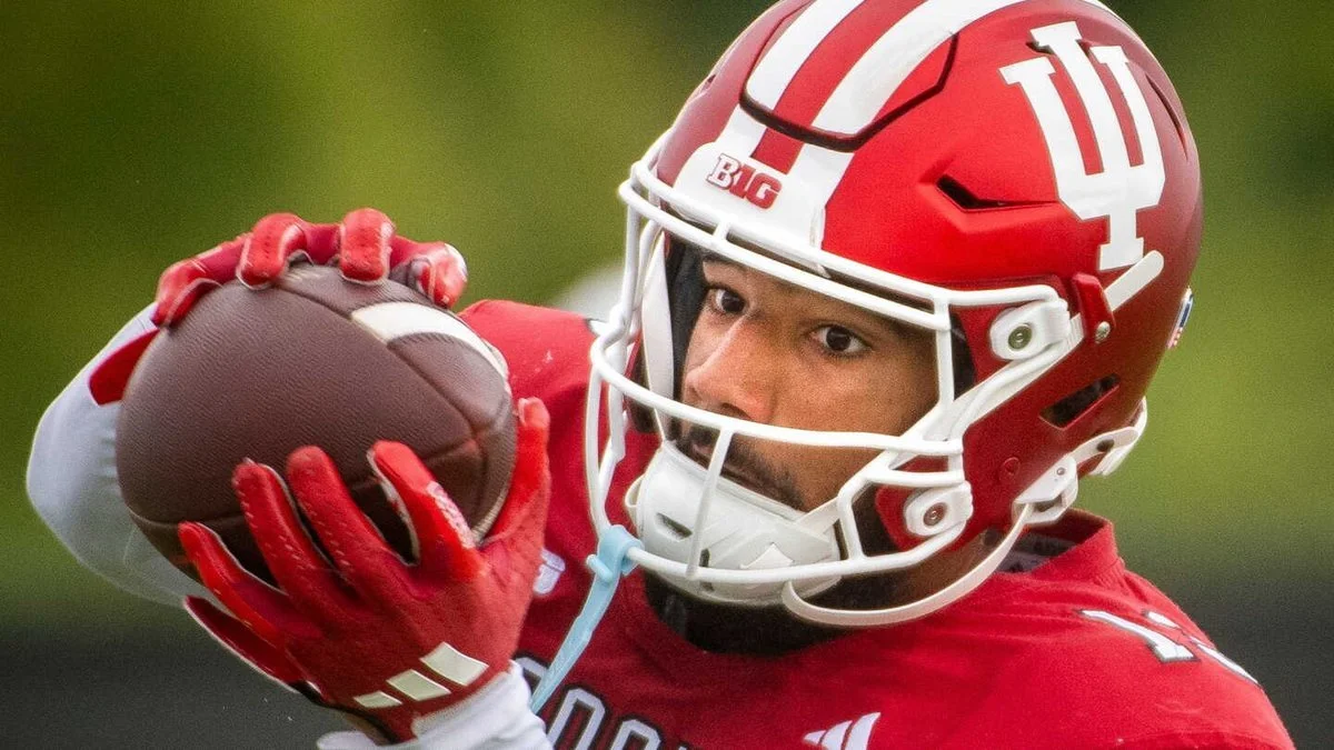 Football player in red helmet and jersey catching a football during a game