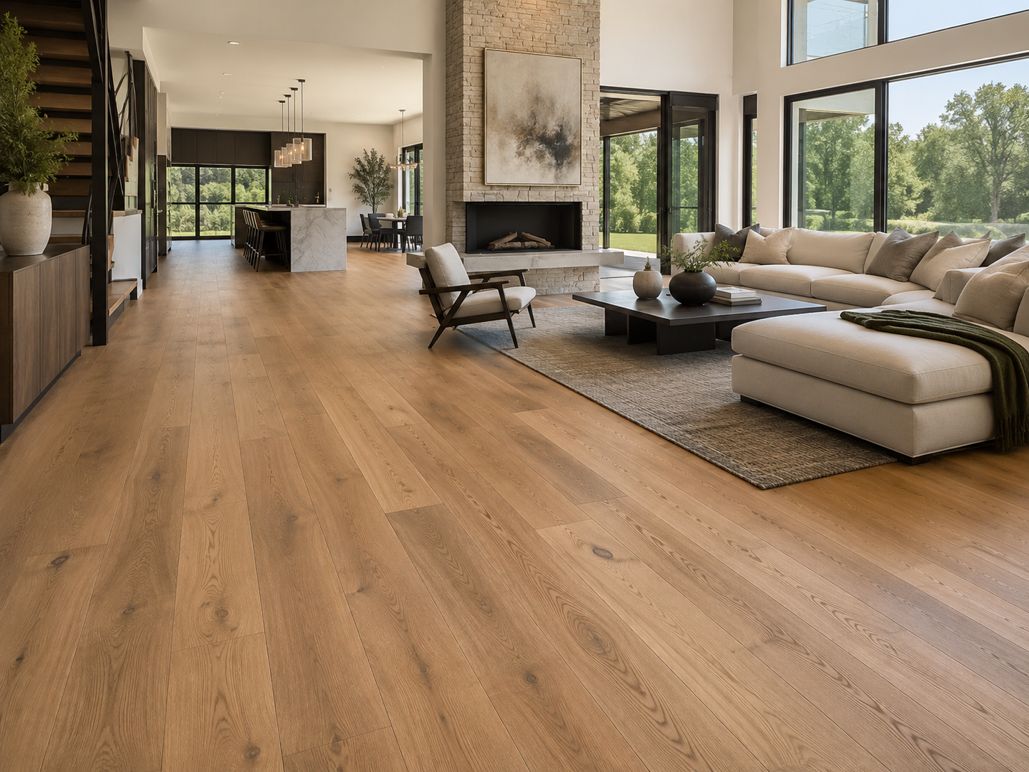 Spacious living room with light wood flooring, modern beige sectional sofa, black coffee table, and large windows with views of green trees.