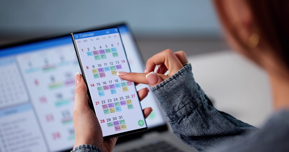 Person using a smartphone with a digital calendar app open, showing scheduled events and appointments.
