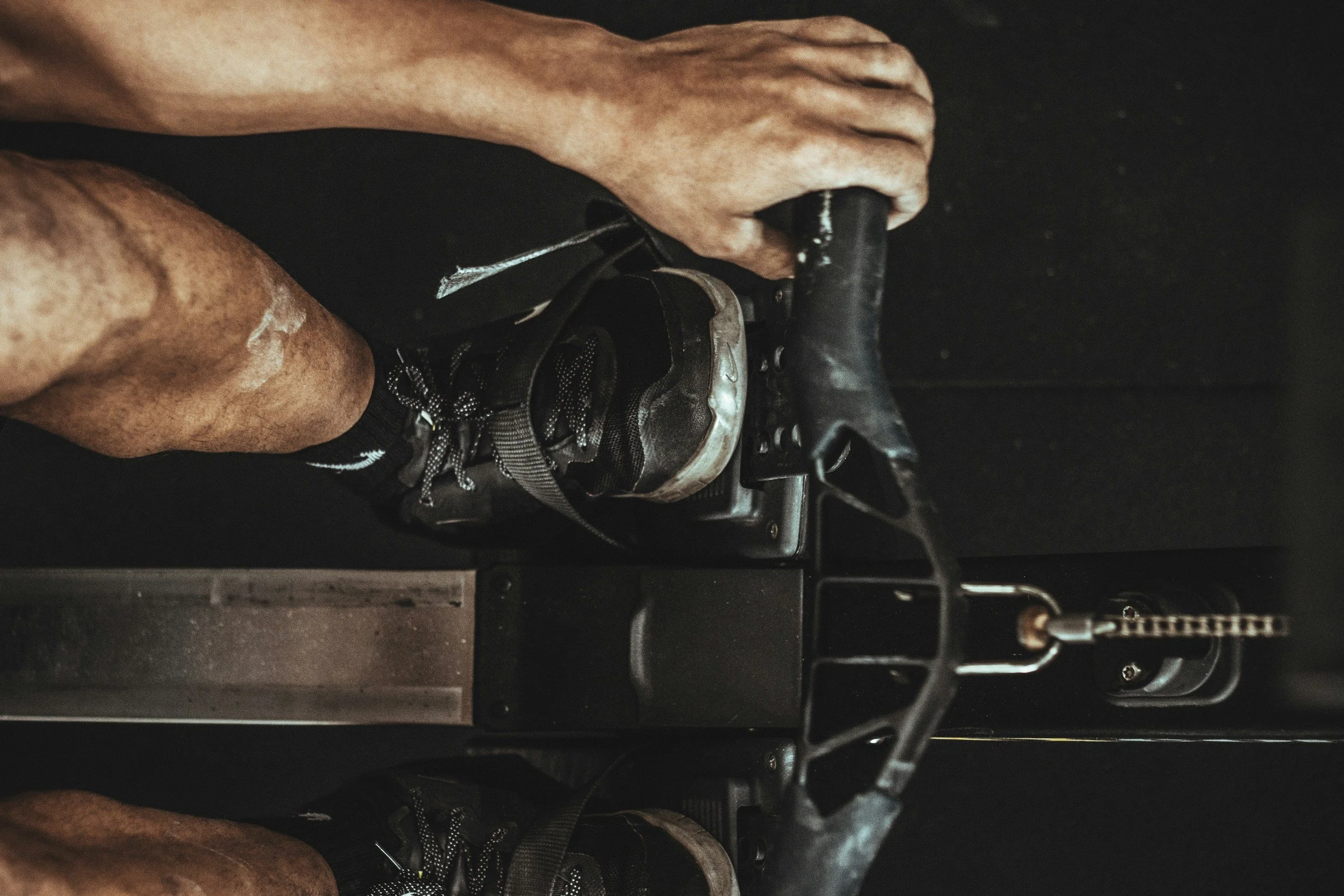 A person wearing hiking boots and shorts, operating a bicycle gear shifter, with their hand on the shifter.