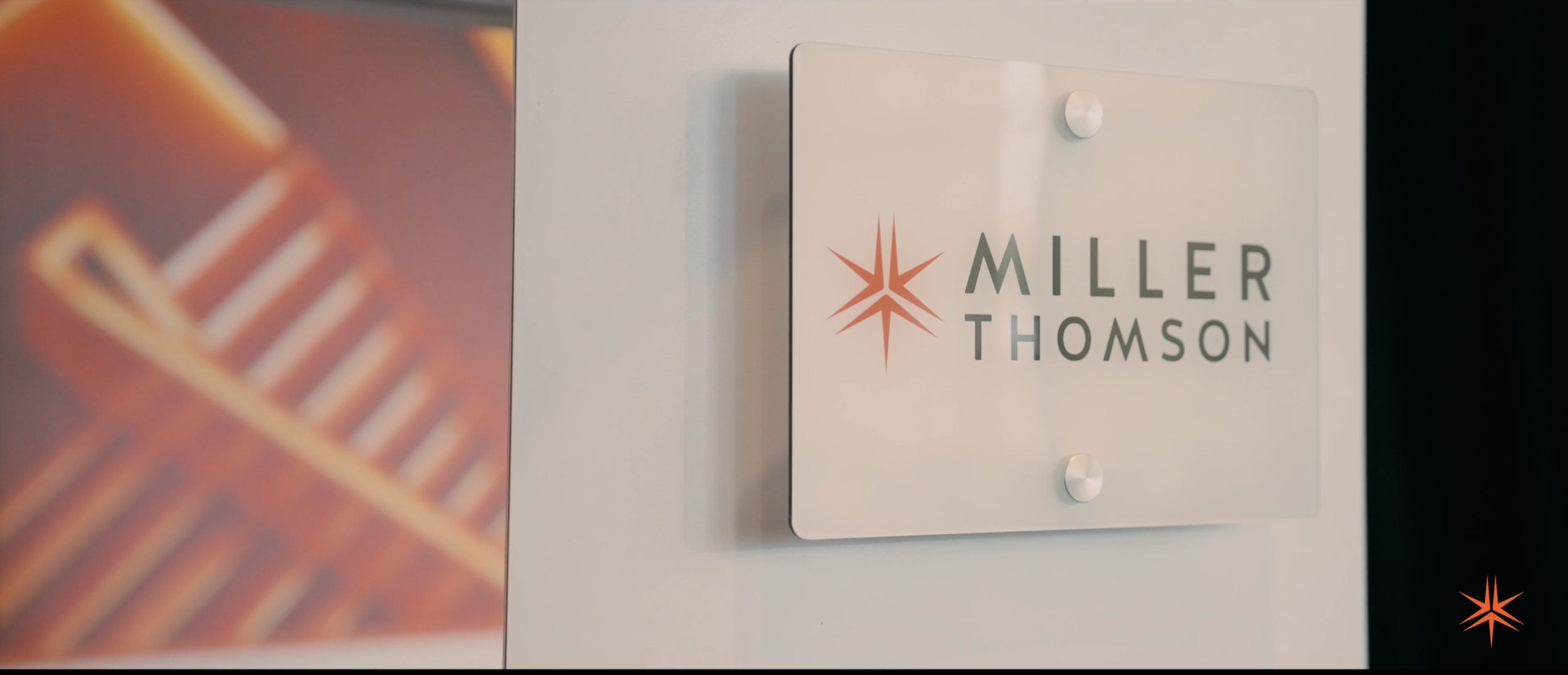 Panneau blanc avec le logo de Miller Thomson apposé dessus. Le logo comprend une étoile orange et le nom de l'entreprise en lettres gris foncé.