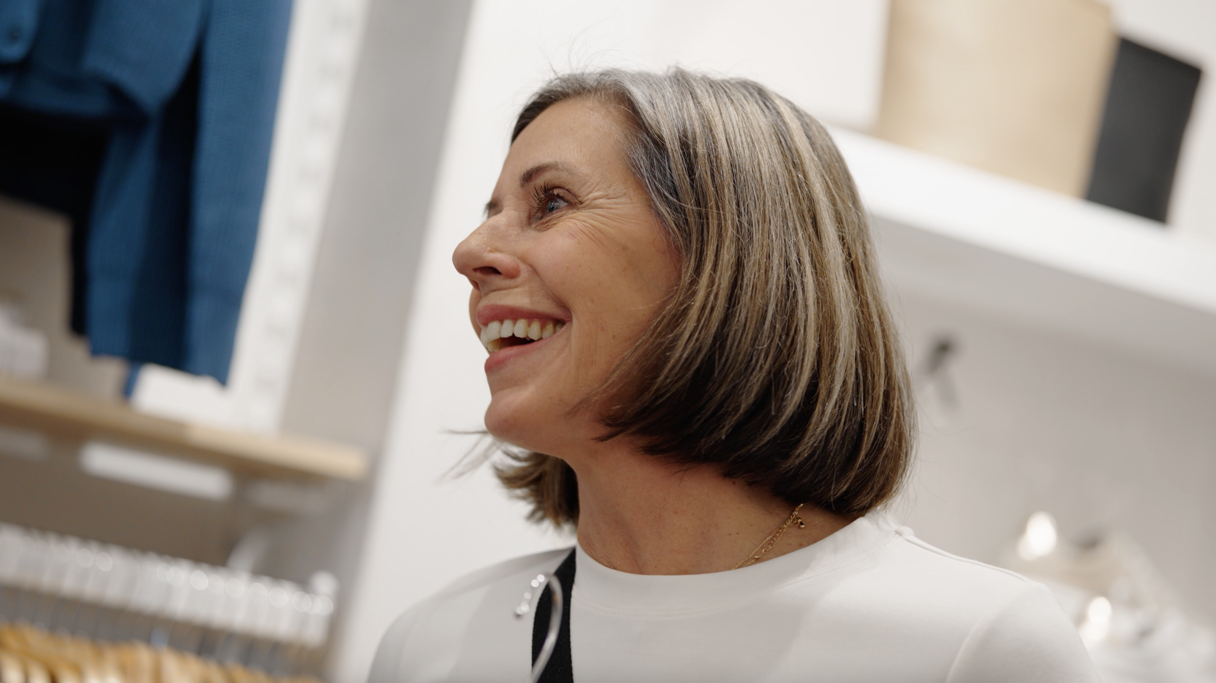 Femme souriante regardant des étagères avec des articles, en intérieur.