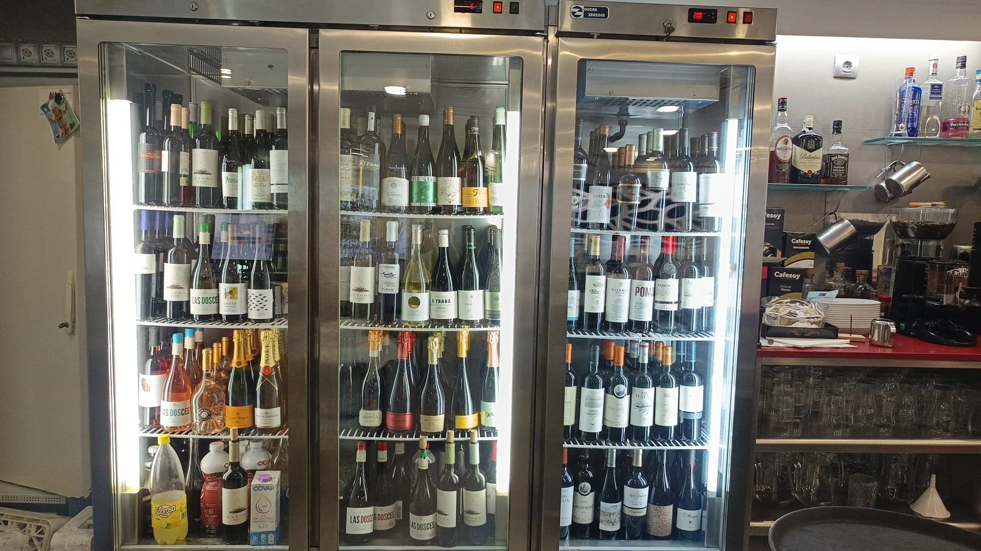 Vitrinas refrigeradas con botellas de vino y otras bebidas alcohólicas en una cafetería o bar.