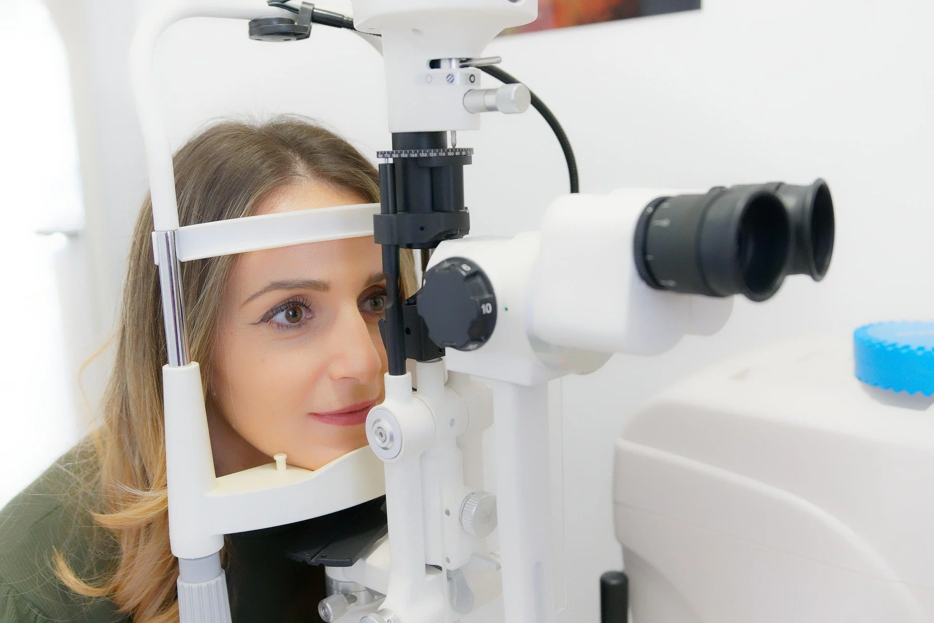 A woman having her eyes examinated with a slit lamp in an optometry office.