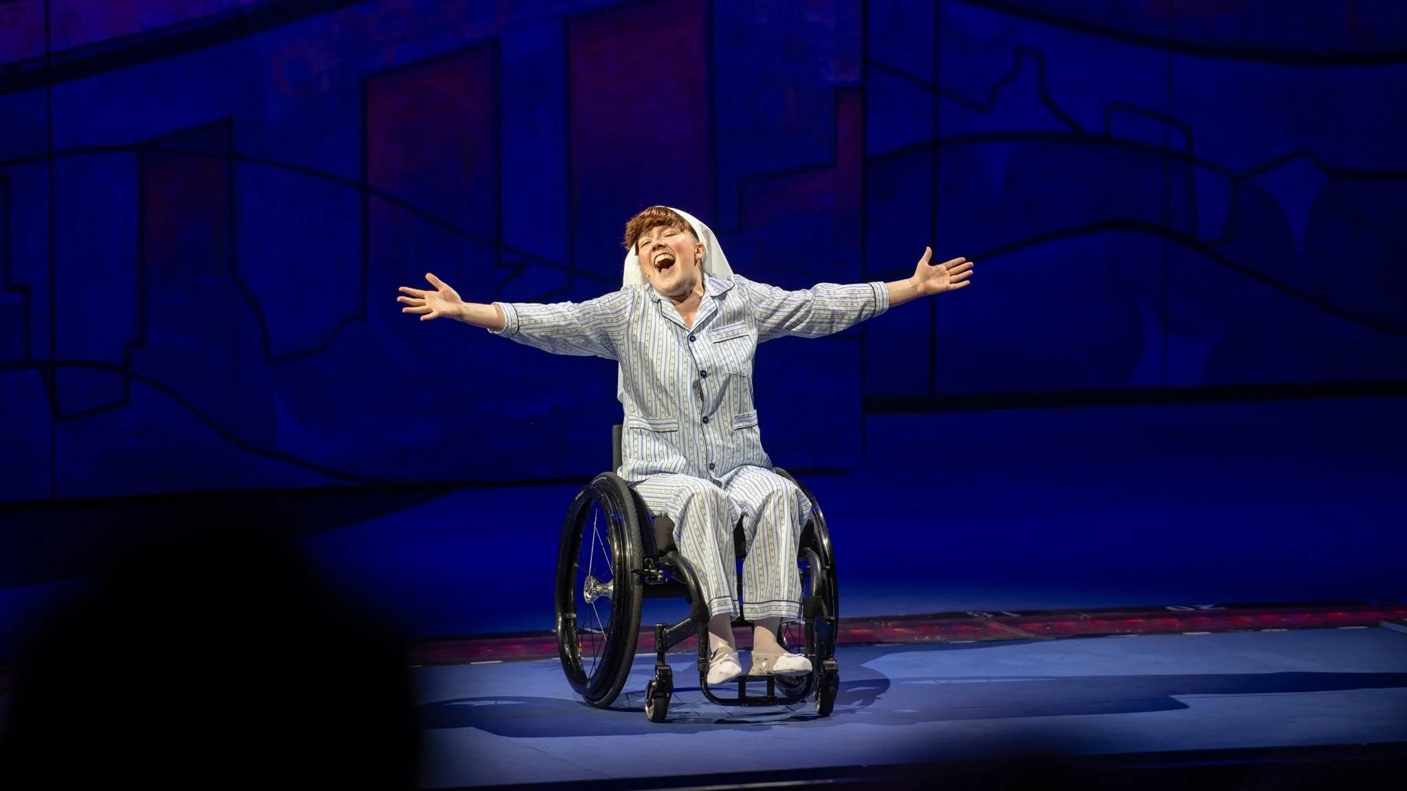 Production still from Sister Act at The Muny, featuring Meredith Aleigha Wells as Sister Mary Robert, singing with arms outstretched.