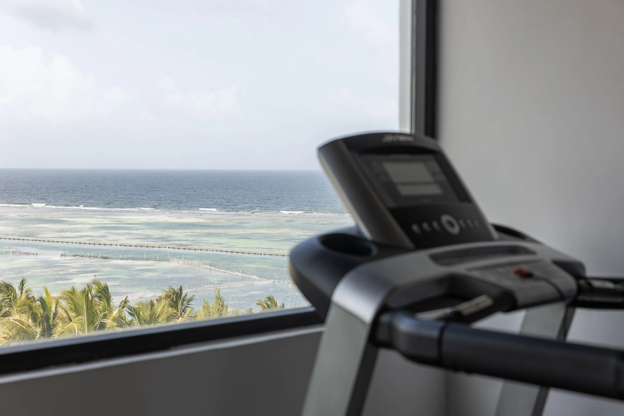 Real estate photography of view of the ocean with waves, seen from inside an airplane or hotel room with a phone placed on a remote control in the foreground, at Mahahual.