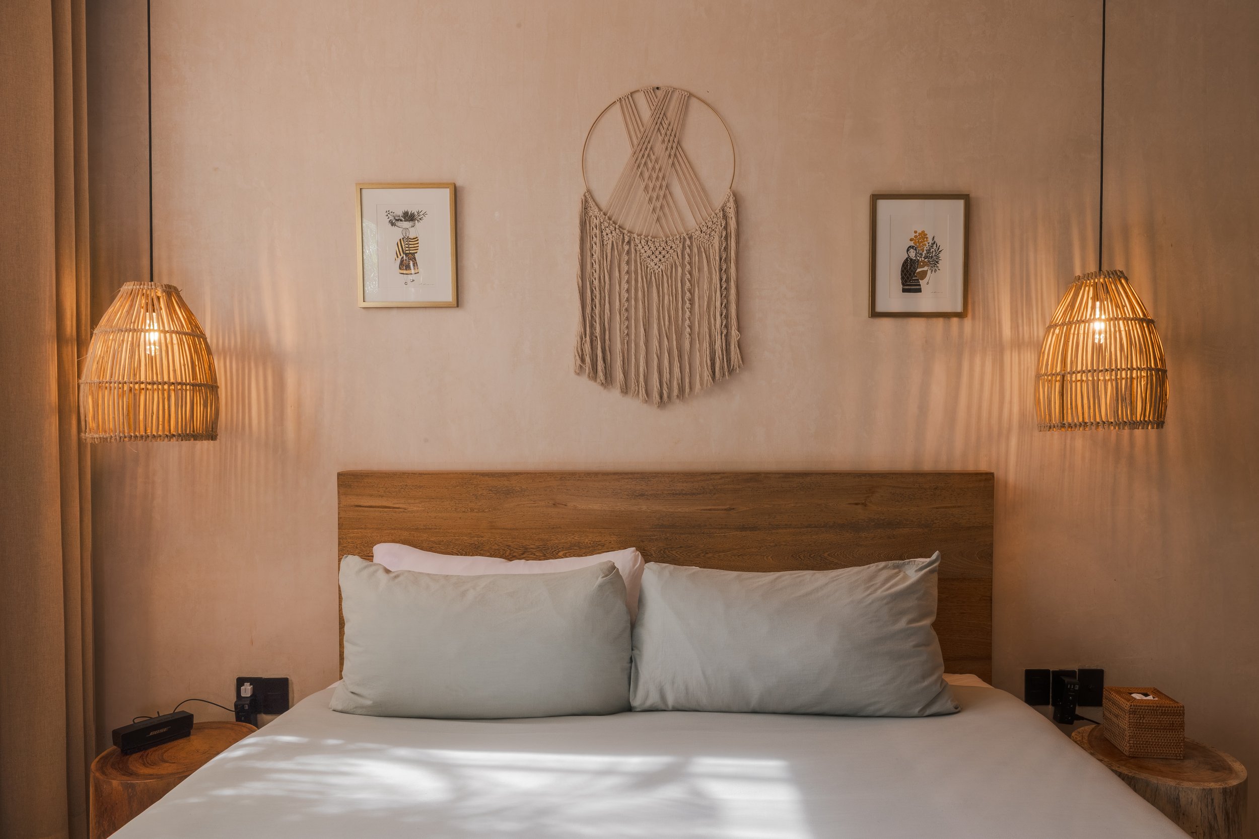 Real estate photography of a neatly made bed with white sheets and pillows in a modern bedroom, at Tulum.