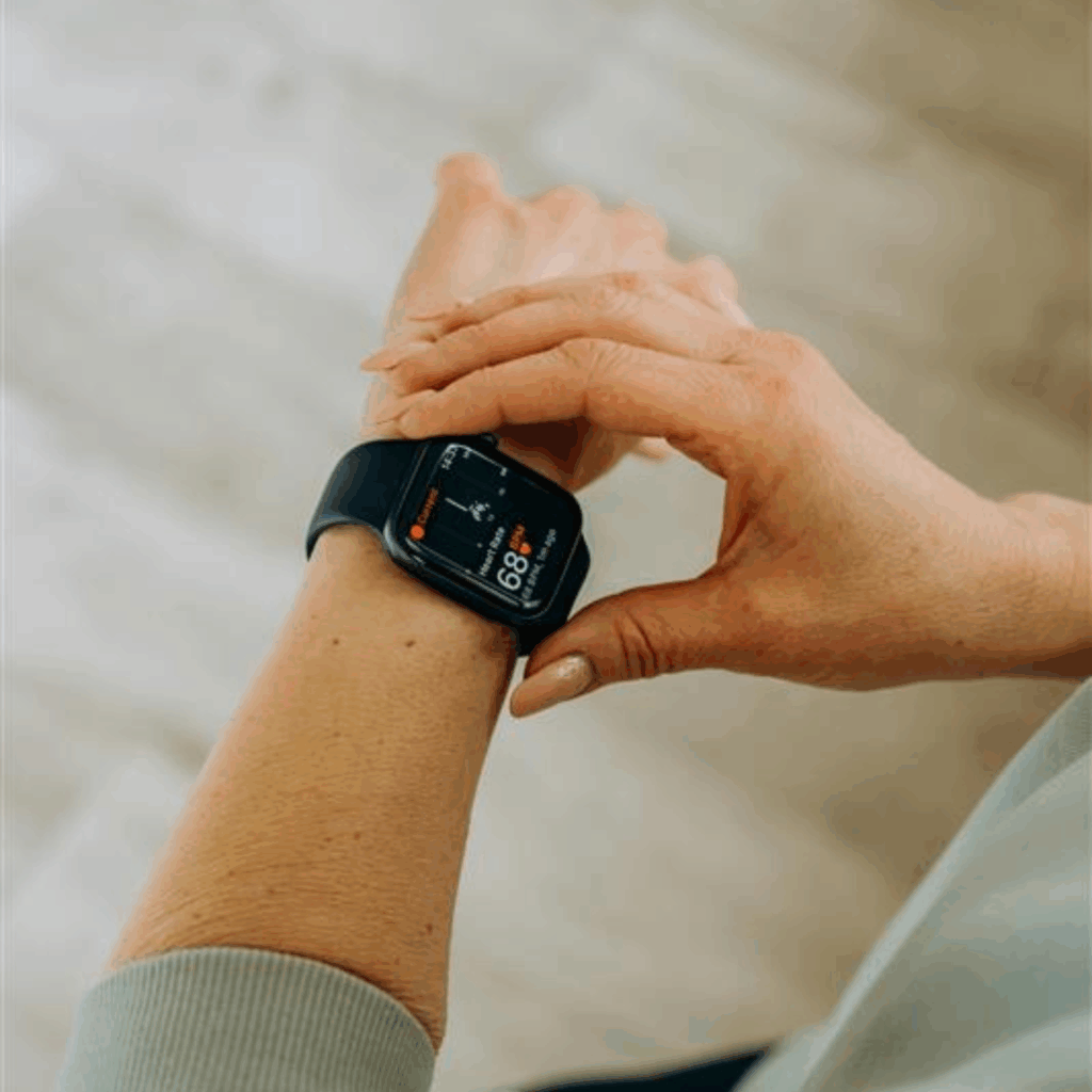 A person wearing a smartwatch on their wrist looking at the display that shows a heart rate of 68.