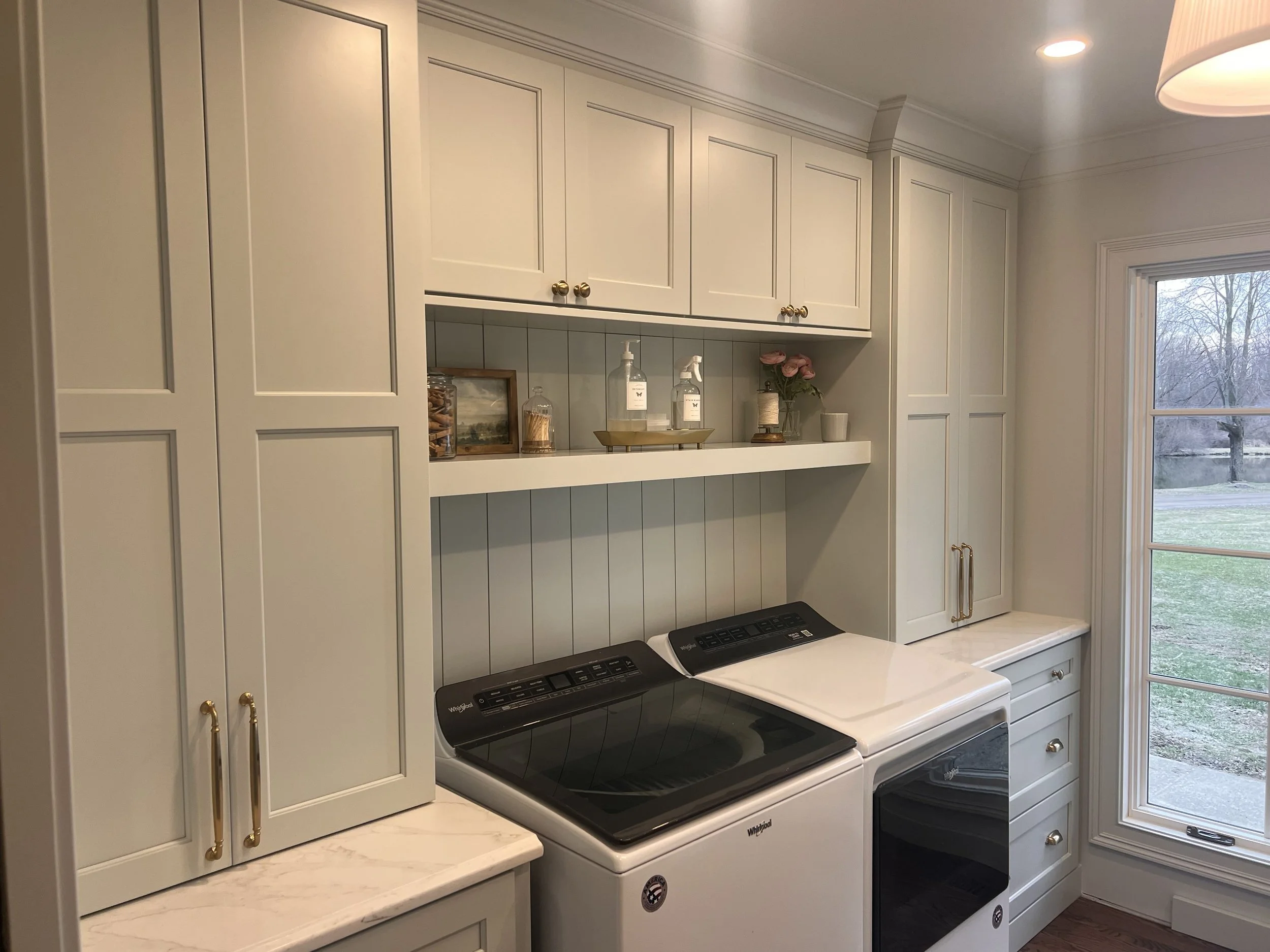 Kitchen with white cabinets, a stove, and a window showing a view of trees and grass outside.