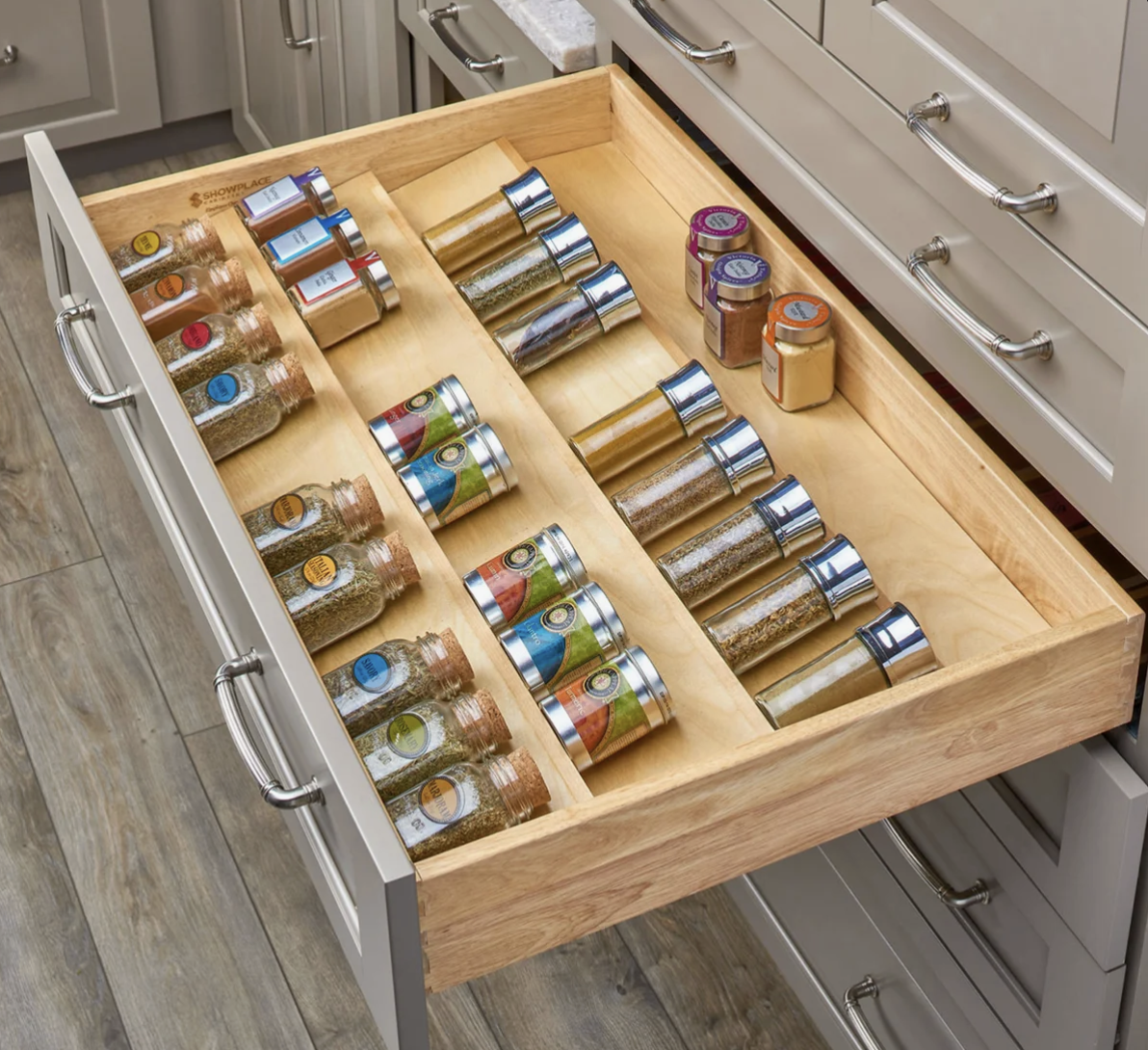 A kitchen drawer in michigan custom build with organized spices in glass jars with labels, arranged in rows.