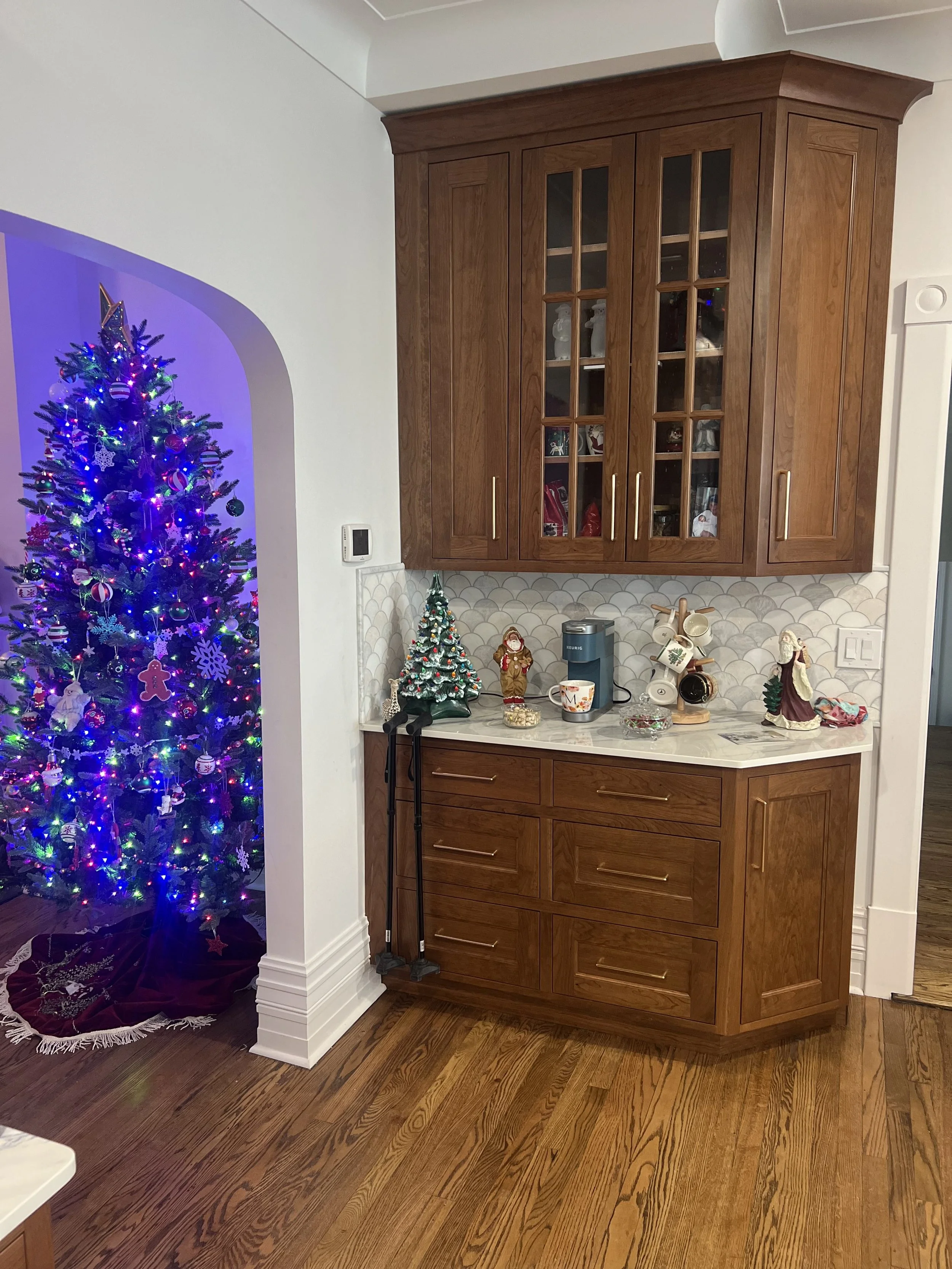 A Christmas tree decorated with colorful lights and ornaments, partially visible on the left side of the image, with a carpeted floor beneath it.