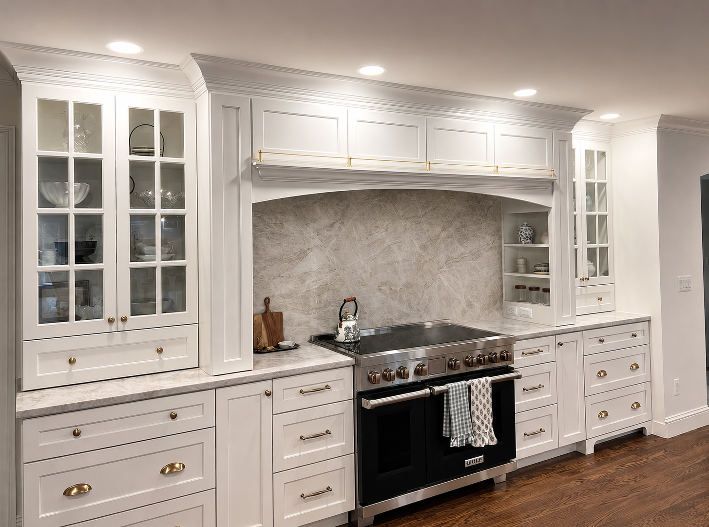 White oxford, MI kitchen with luxurious cabinetry, glass-front upper cabinets, marble countertops, a black and stainless steel stove, and wooden drawers with gold handles.