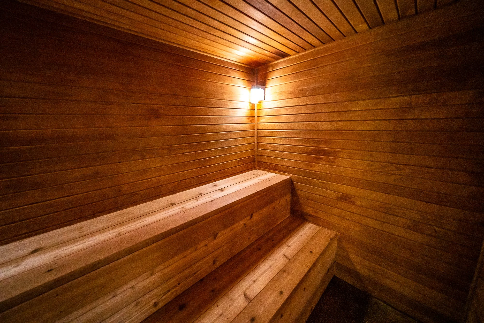 Interior of a wooden sauna with a bench along the wall and a wall-mounted light