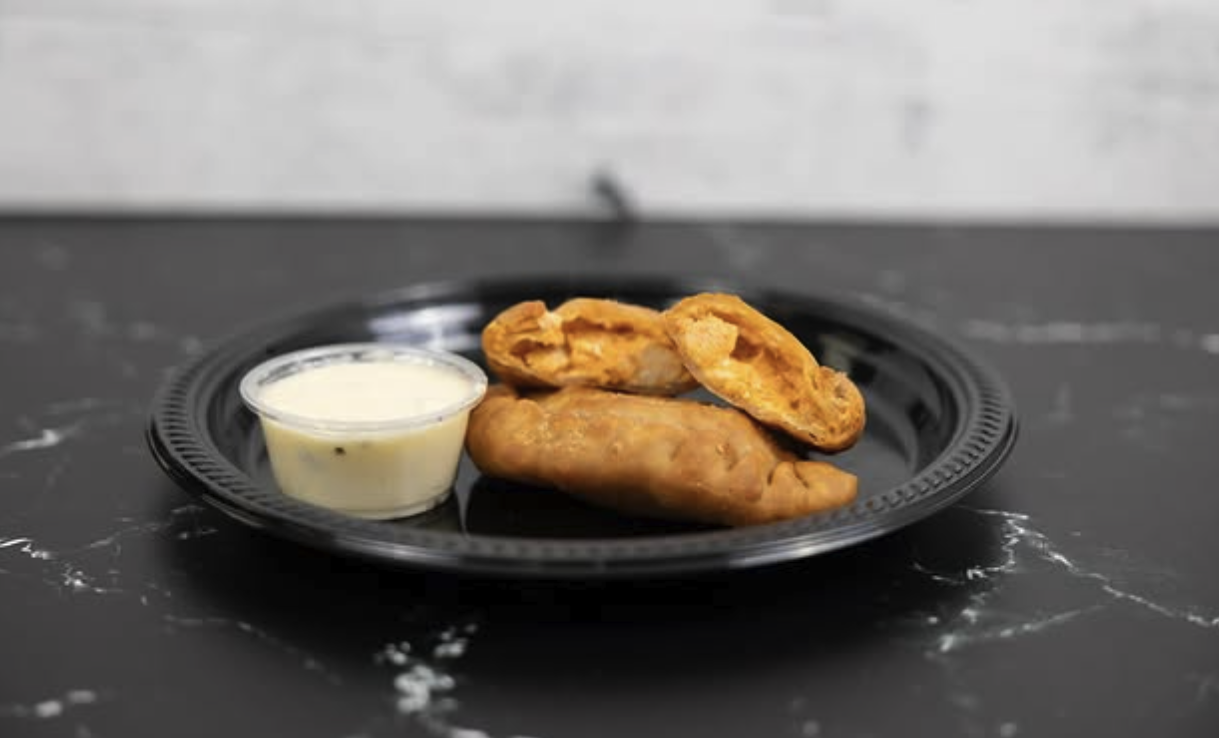 Plate with three chicken taquitos and a side of white dipping sauce.