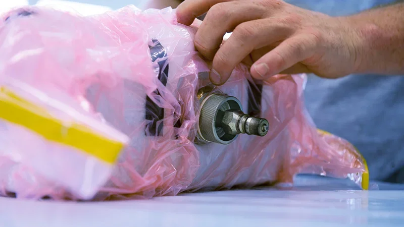 A person vacuum bagging a small composite layup part.