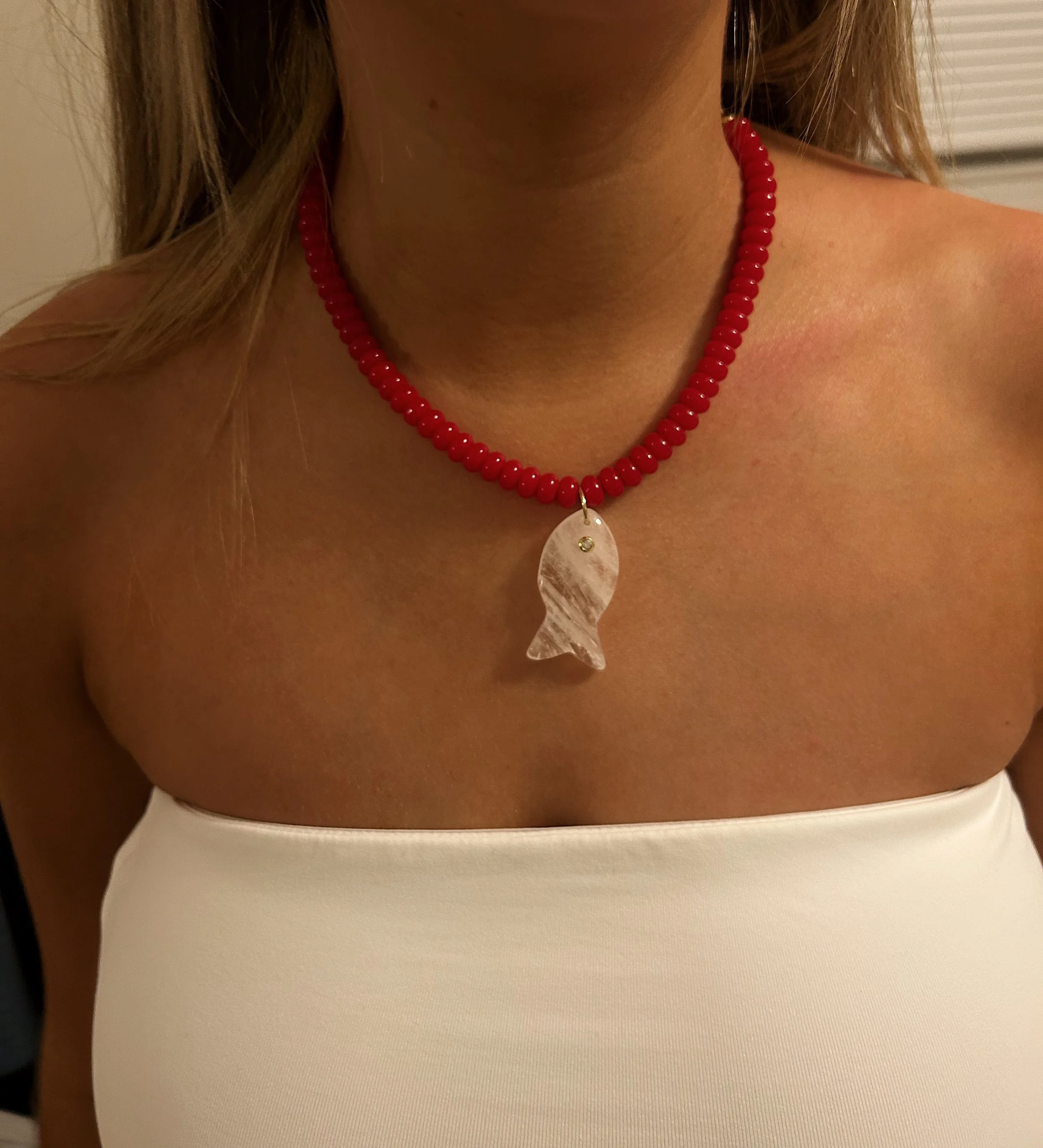 A person wearing a necklace with a shell pendant.