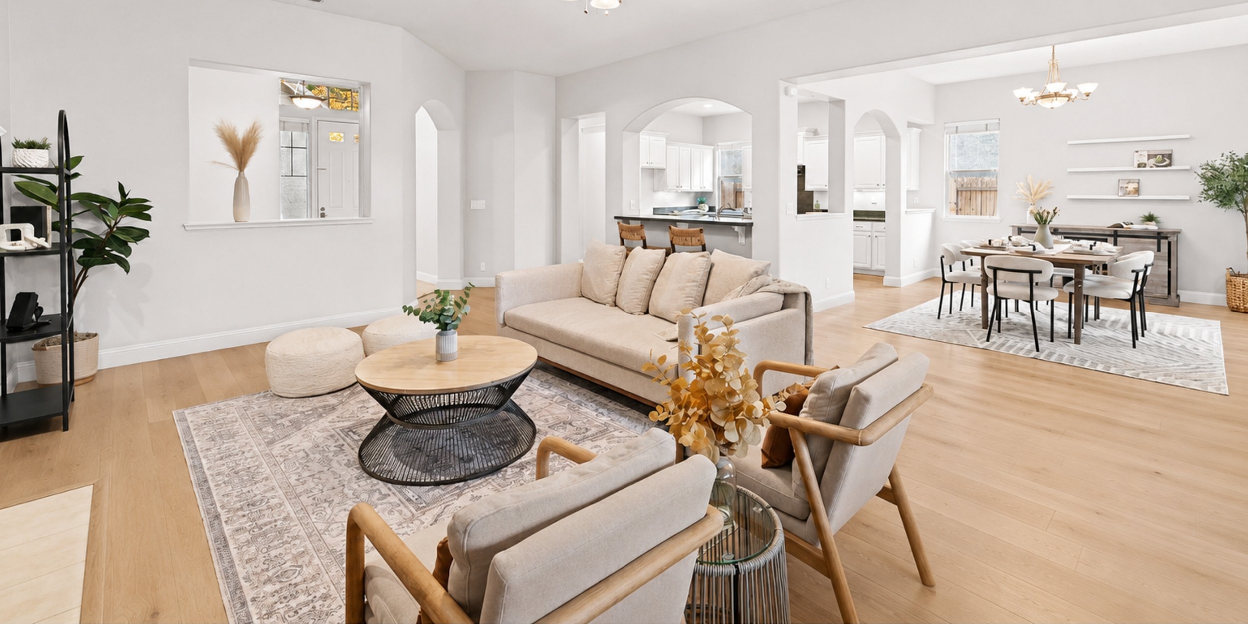 Bright, spacious open-plan living and dining area with light-colored walls, wooden flooring, beige and cream furniture, plants, and modern decor.