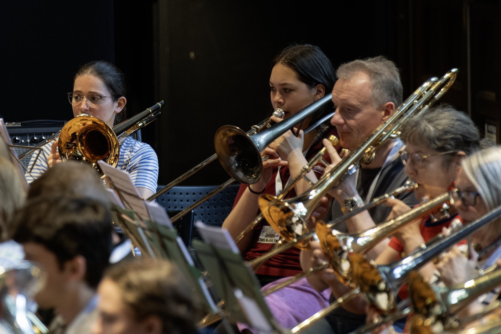 A group of musicians playing brass instruments in an orchestra, including trumpets and trombones, during a performance.