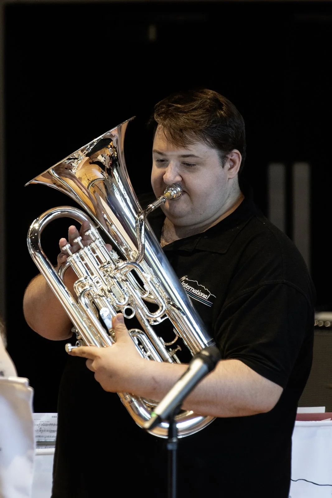 A man playing a silver euphonium in a music setting.