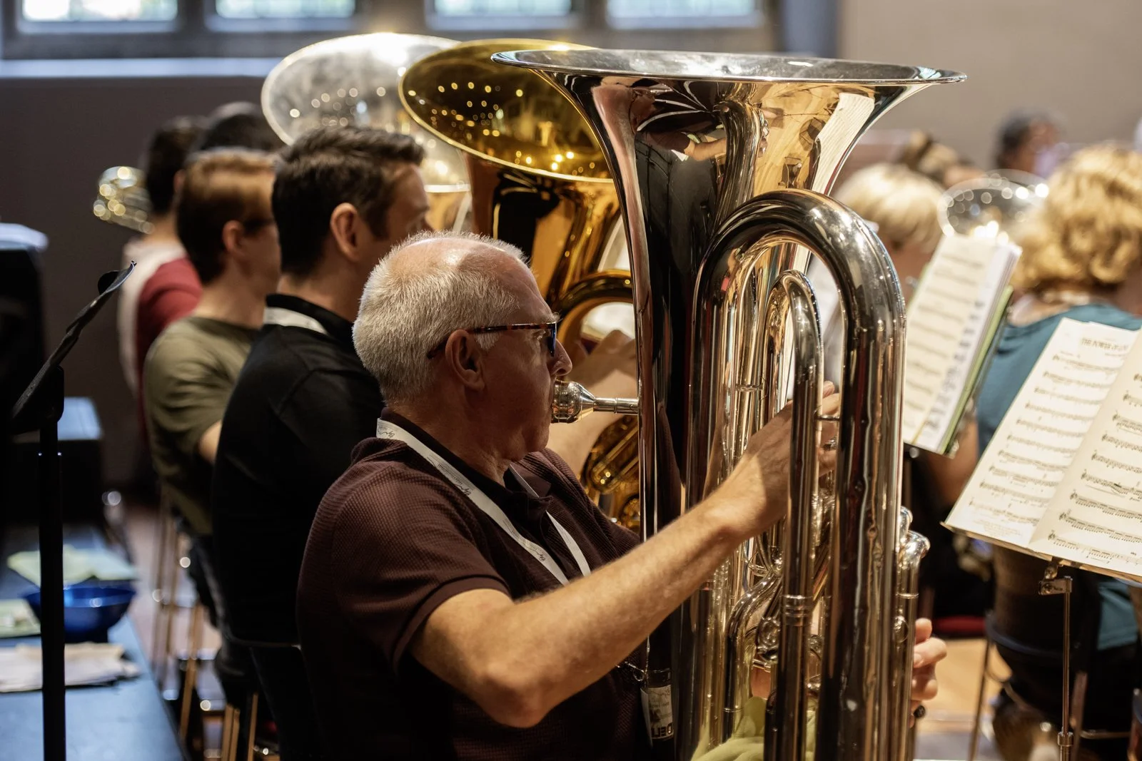Group of musicians playing brass instruments in an orchestra, focusing on a man playing a tuba.
