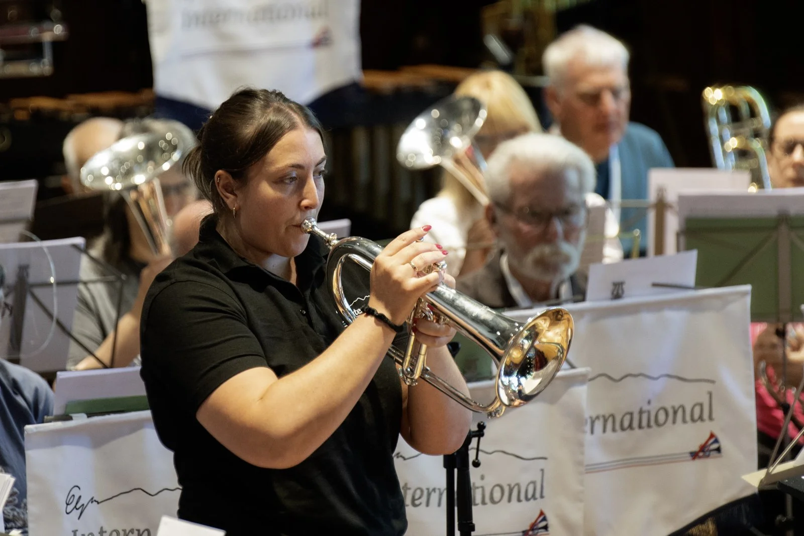 A woman playing a silver trumpet as part of an orchestra at a concert.