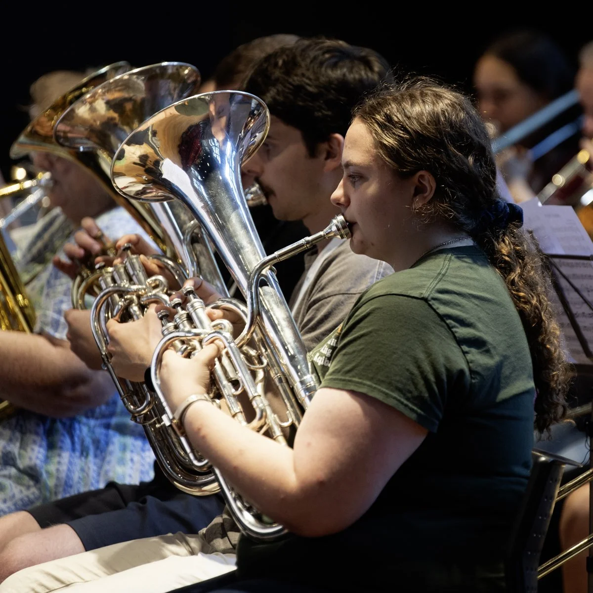 Young woman playing the French horn in an orchestra.