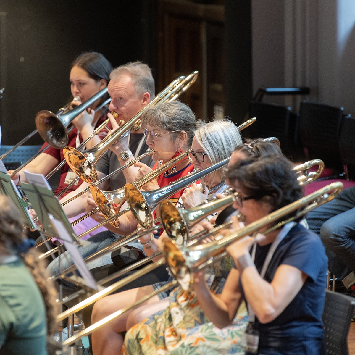 Group of musicians playing trombones during an orchestral rehearsal.
