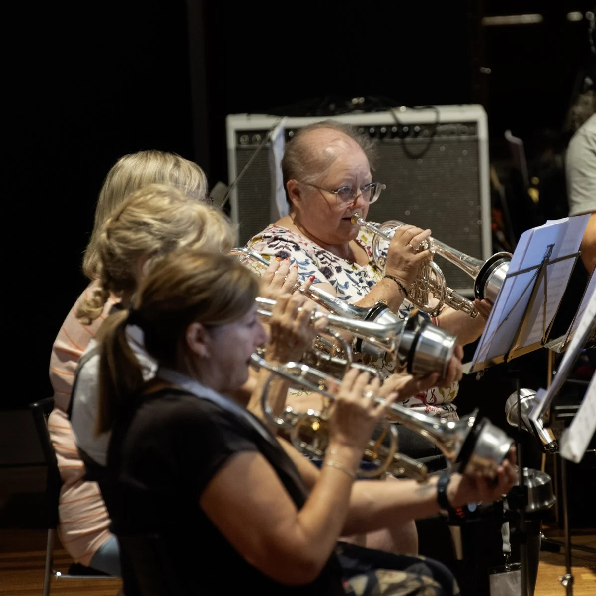 Older women playing saxophones in a band practice session.