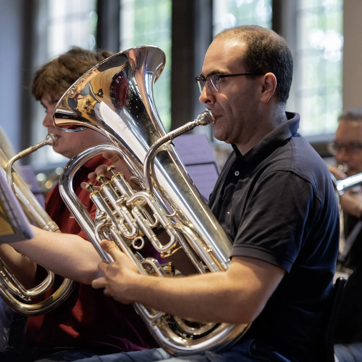 Musicians playing brass instruments in an orchestra rehearsal.
