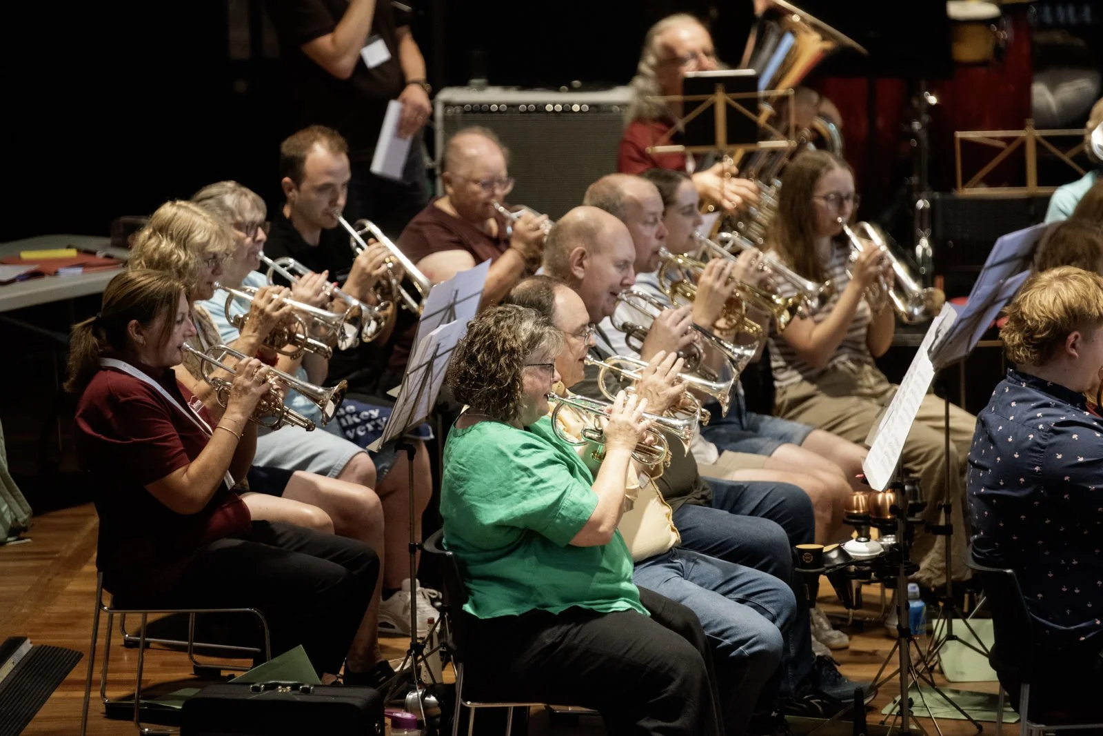 A group of people playing trumpets during an orchestra rehearsal.