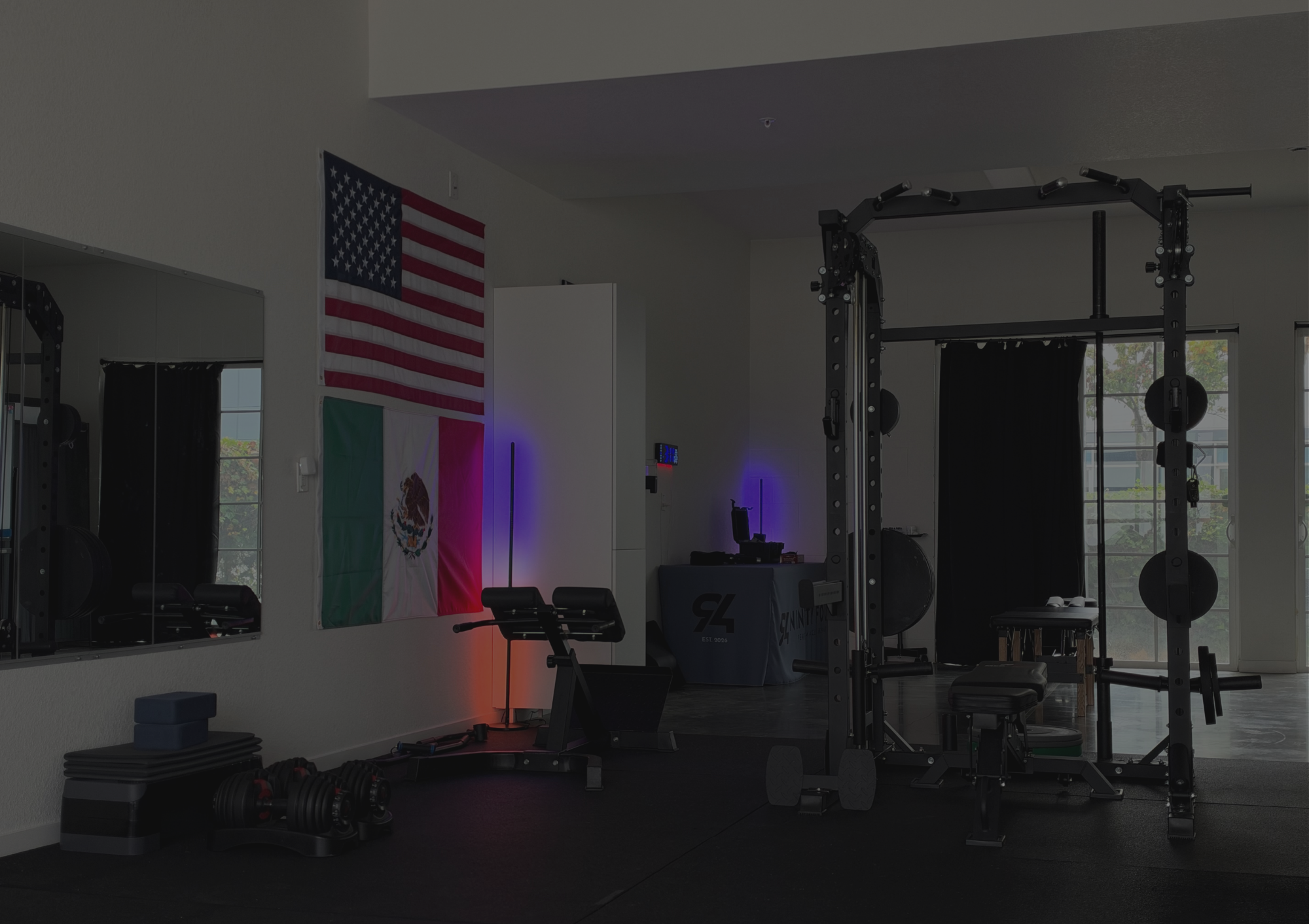 Training area at Ninety Four Performance & Rehab in Richmond, CA, with a power rack, dumbbells, and rowing machine for strength-based rehab